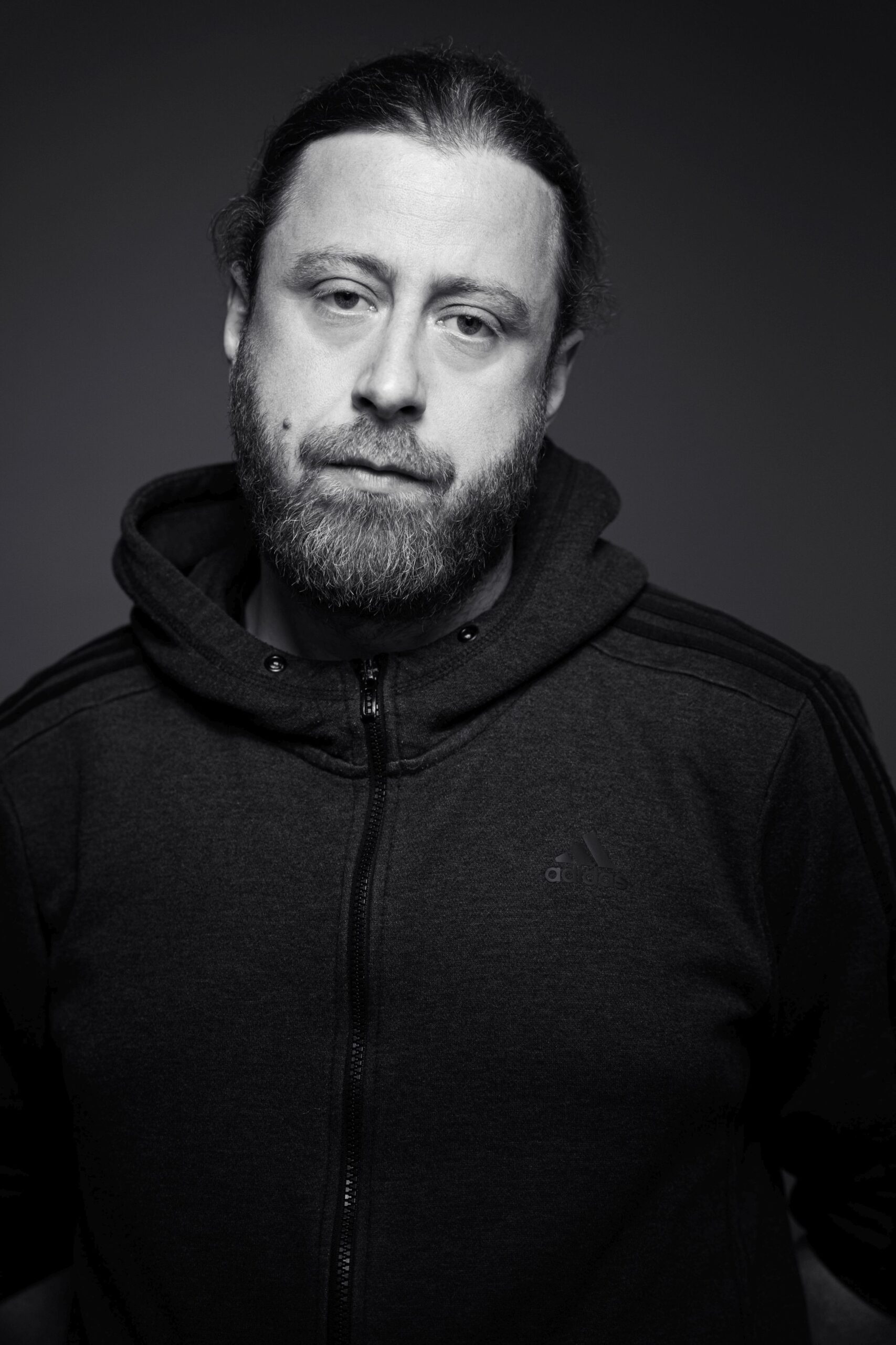 Das Schwarz-Weiss-Foto zeigt den Rapper Keeko aus dem Ruhrgebiert. Er trägt eine dunkle Kapuzenjacke und sieht direkt in die Kamera. Er hat einen ernsten Gesichtsausdruck. Das Bild hat Fotograf Toni Borgert aufgenommen.