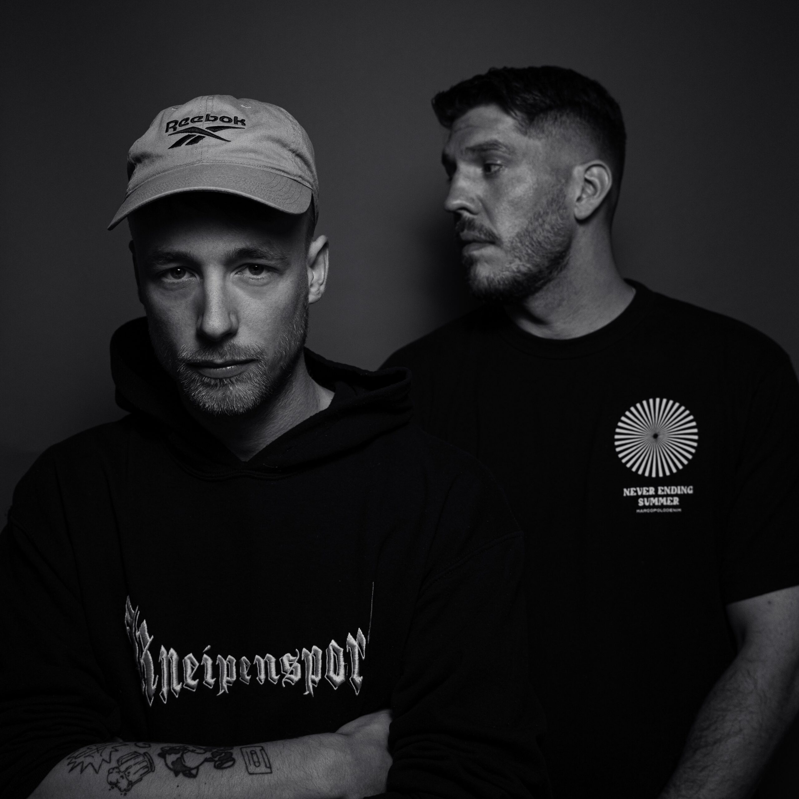 Das Bild ist das Single-Cover zur Single "Winterdrepression" von Adrinalin und Inkasso. Adrinalin steht weiter vorne im Bild hat verschränkte Arme und sieht in die Kamera. Er trägt eine Kappe und einen schwarzen Pullover mit einem Schriftzug. Der Rapper Inkasso steht hinter ihm und schaut nach rechts. Er trägt ein schwarzes T-Shirt. Das Foto wurde von Fotograf Toni Borgert aufgenommen.