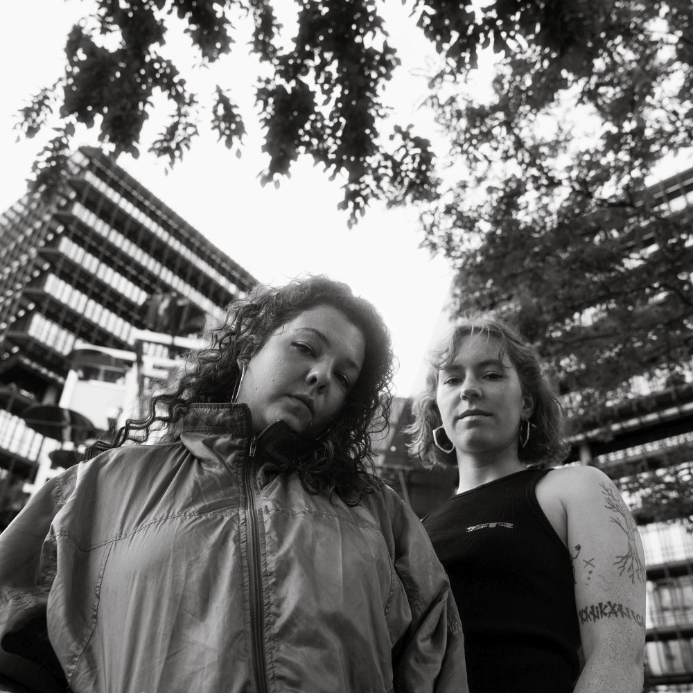 Das Foto ist das Album-Cover zu "La Ville Move" der Rapperinnen Zora und Moen. Das Bild zeigt Moen auf der rechten Seite, und Zora auf der linken Seite. Moen hat dunkle, lockige Haare und trägt eine Jacke aus Ballonseide. Zora steht neben ihr, leicht eingedreht. Sie hat hellere Schulterlange Haare und trägt ein schwarzes Top ohne Ärmel. Die beiden sehen genau in die Kamera. Das Foto wurde von Fotograf Toni Borgert fotografiert.